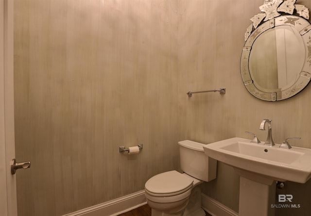 bathroom featuring toilet, baseboards, and a sink