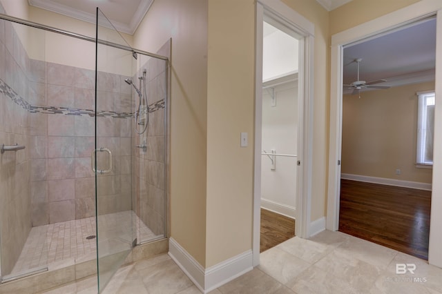 bathroom with ornamental molding, a shower stall, a walk in closet, and baseboards