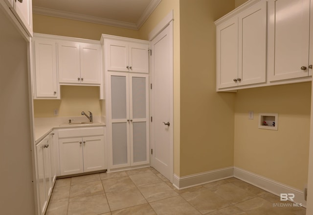 clothes washing area featuring washer hookup, a sink, baseboards, cabinet space, and crown molding