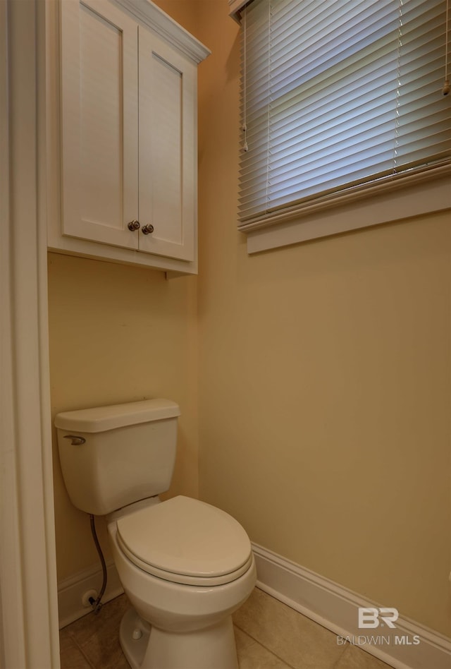 bathroom with toilet, baseboards, and tile patterned floors