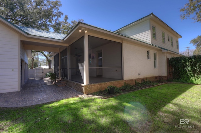 rear view of house featuring a yard, a patio, a sunroom, crawl space, and metal roof