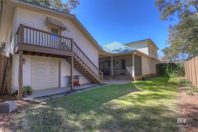 back of property featuring a lawn, a sunroom, metal roof, stairs, and fence