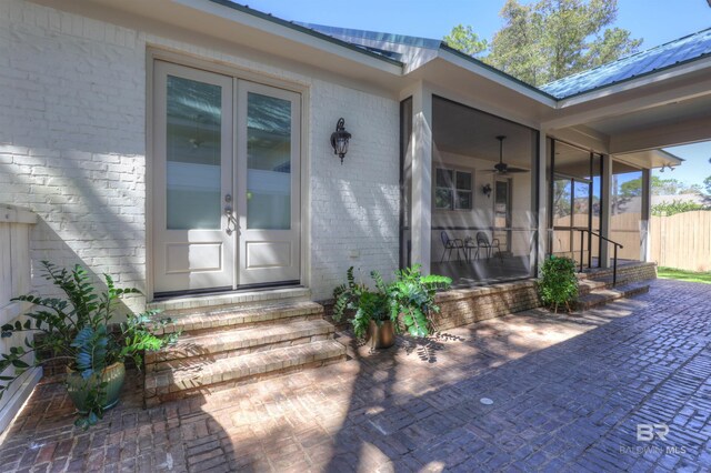 entrance to property with metal roof, french doors, brick siding, and fence