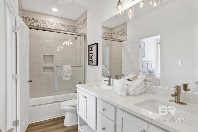 full bathroom featuring vanity, hardwood / wood-style flooring, toilet, and combined bath / shower with glass door
