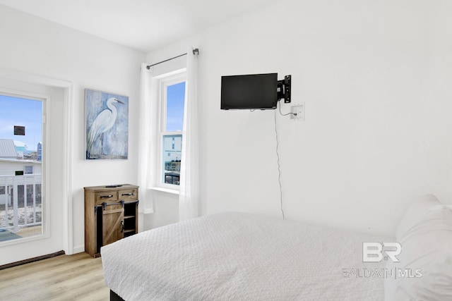 bedroom with multiple windows and light hardwood / wood-style flooring