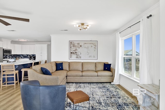 living room featuring ceiling fan, ornamental molding, and light hardwood / wood-style flooring