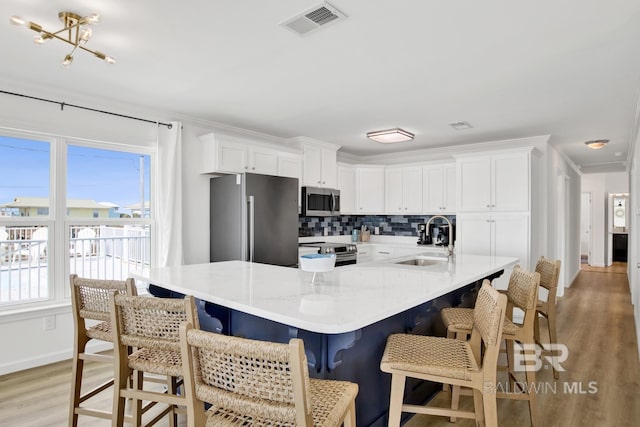 kitchen with white cabinetry, appliances with stainless steel finishes, sink, and a kitchen bar