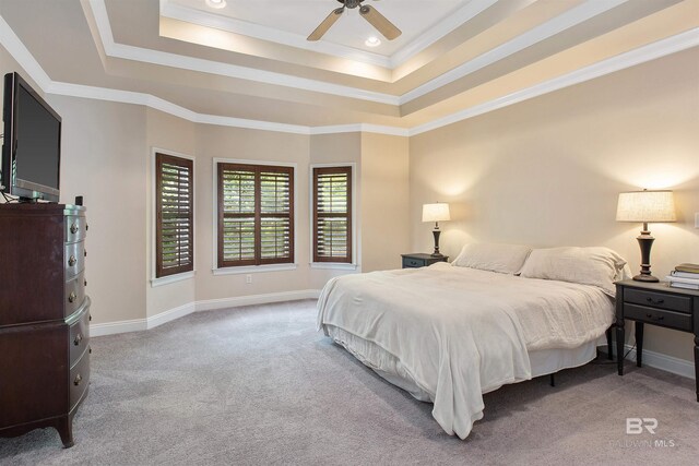 bedroom with light colored carpet, a raised ceiling, ornamental molding, and ceiling fan