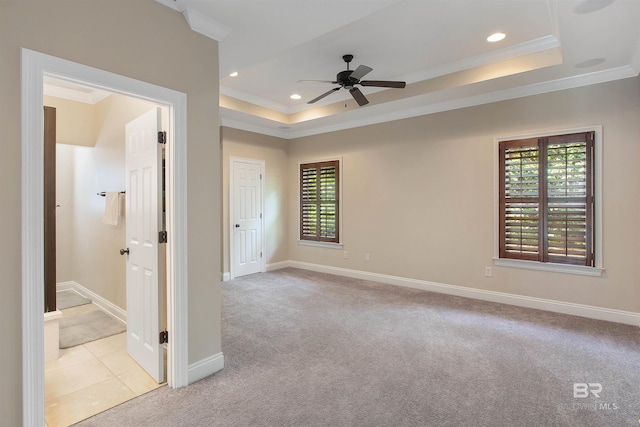 spare room featuring light carpet, crown molding, a tray ceiling, and ceiling fan