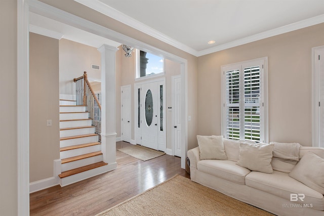 entryway with crown molding, decorative columns, a healthy amount of sunlight, and light hardwood / wood-style flooring