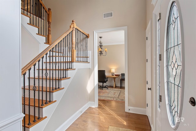 entryway with a notable chandelier, light hardwood / wood-style flooring, and ornamental molding