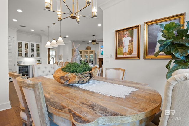 dining area featuring beverage cooler, recessed lighting, wood finished floors, and ornamental molding