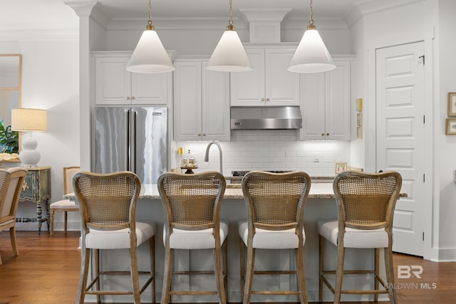 kitchen with under cabinet range hood, dark wood finished floors, tasteful backsplash, and freestanding refrigerator