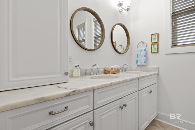 bathroom with baseboards, double vanity, and a sink