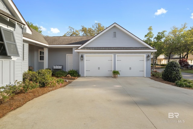 view of front of home with an attached garage, concrete driveway, roof with shingles, and board and batten siding