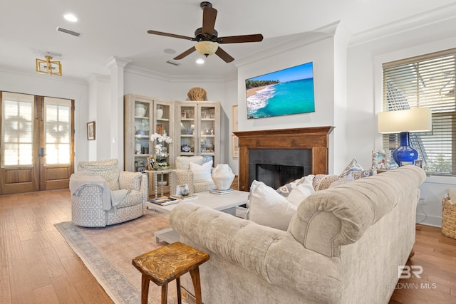 living room featuring a fireplace, ornamental molding, wood finished floors, ceiling fan, and french doors