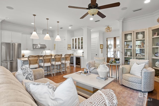 living area with ceiling fan, visible vents, and crown molding