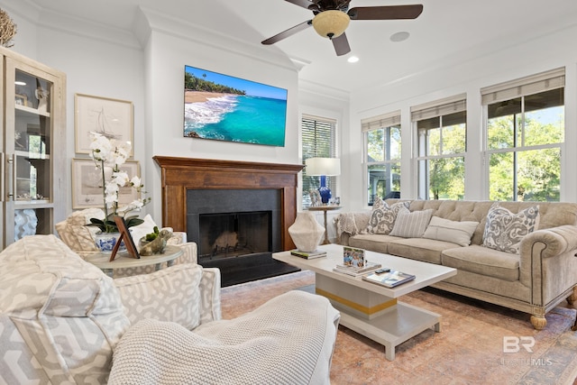 living area featuring recessed lighting, a fireplace with raised hearth, ornamental molding, and a ceiling fan