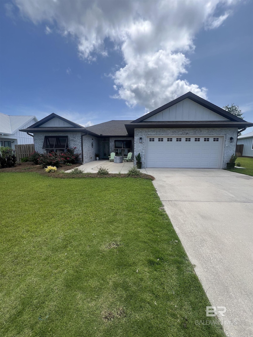 1244 Dorado Way, Gulf Shores, AL 36542 - ranch-style home with a garage, concrete driveway, a front yard, and board and batten siding