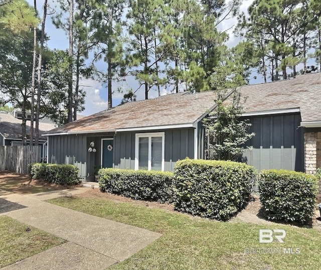 view of front of house featuring fence, a front lawn, and board and batten siding