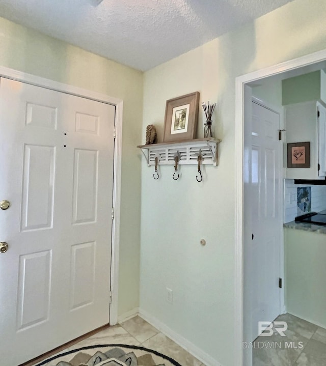 entryway with baseboards and a textured ceiling