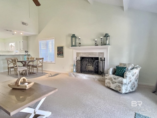 carpeted living room with baseboards, visible vents, a fireplace, high vaulted ceiling, and beam ceiling