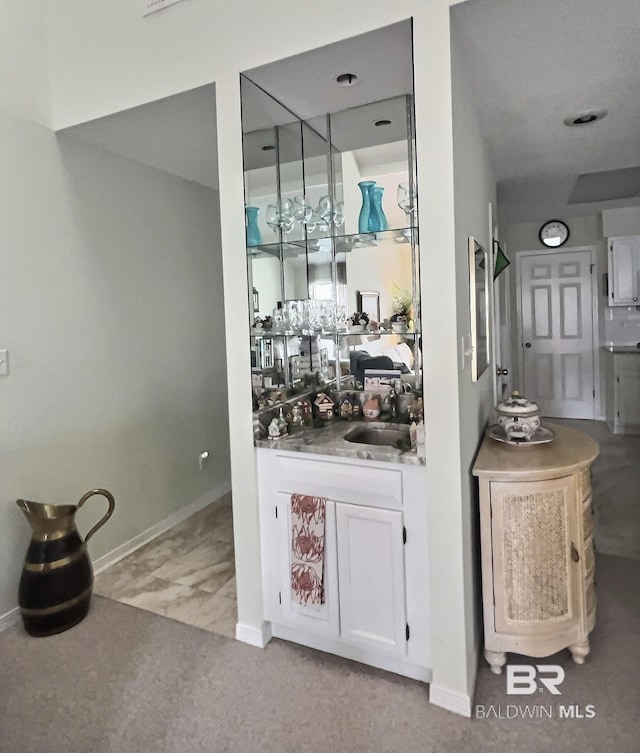 bar featuring a sink, baseboards, and indoor wet bar