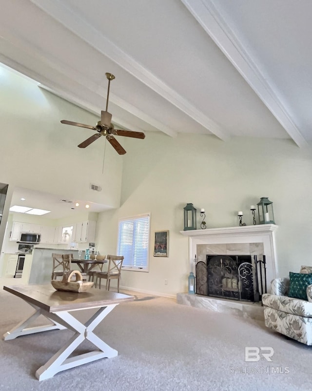 living area featuring high vaulted ceiling, visible vents, a high end fireplace, beam ceiling, and carpet