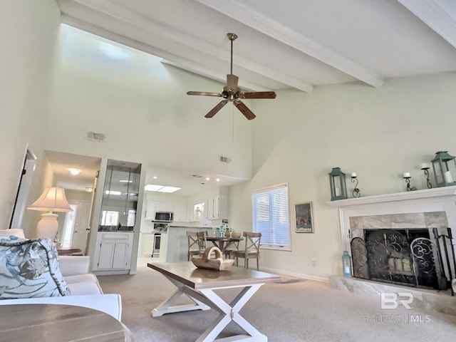 living room with beam ceiling, a fireplace, visible vents, a towering ceiling, and light carpet