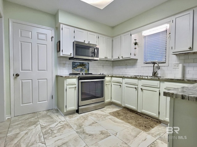 kitchen featuring appliances with stainless steel finishes, marble finish floor, a sink, and backsplash