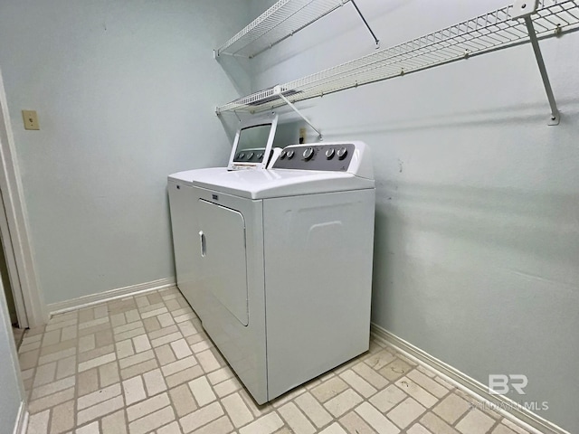 laundry area featuring laundry area, washer and clothes dryer, brick floor, and baseboards