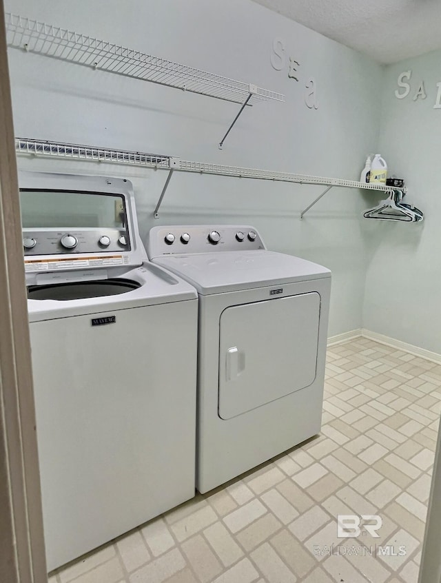 clothes washing area with laundry area, separate washer and dryer, and baseboards