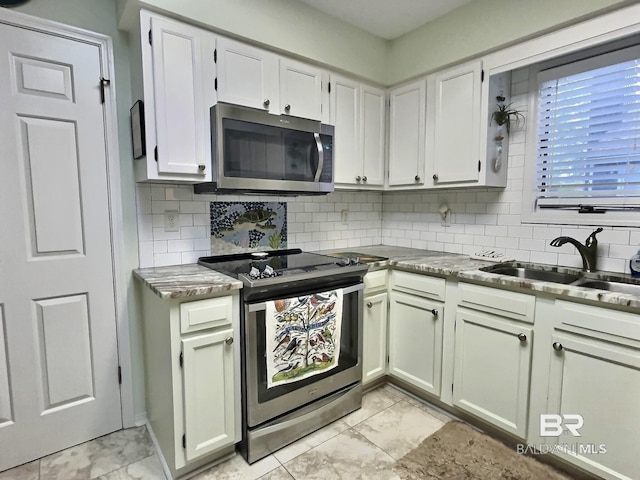 kitchen with marble finish floor, decorative backsplash, stainless steel appliances, and a sink