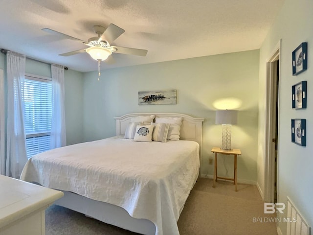 bedroom featuring carpet, baseboards, ceiling fan, and a textured ceiling