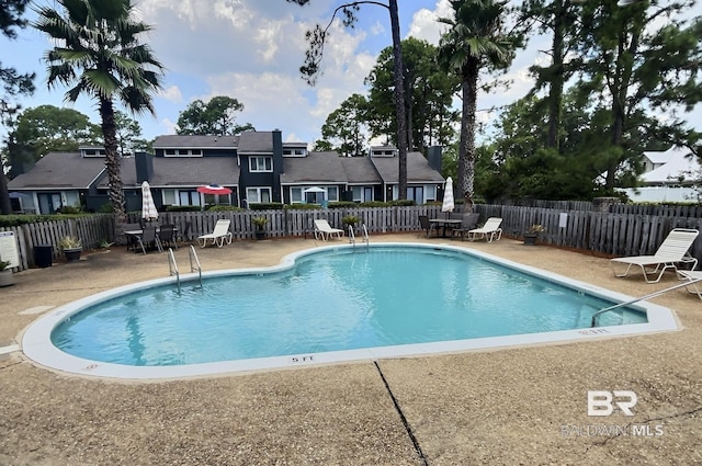 community pool featuring a residential view, fence, and a patio