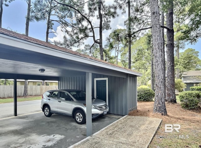 view of vehicle parking featuring fence and a carport