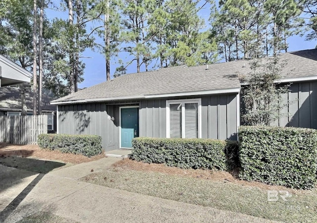 view of front of house with fence, board and batten siding, and roof with shingles