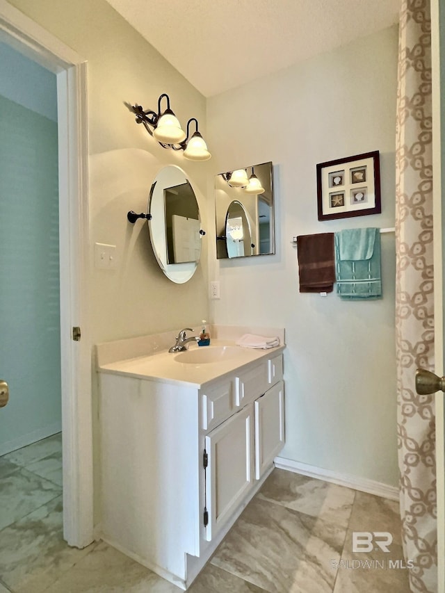 bathroom with marble finish floor, vanity, and baseboards