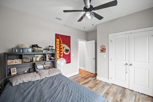 bedroom with a closet, light wood finished floors, baseboards, visible vents, and ceiling fan