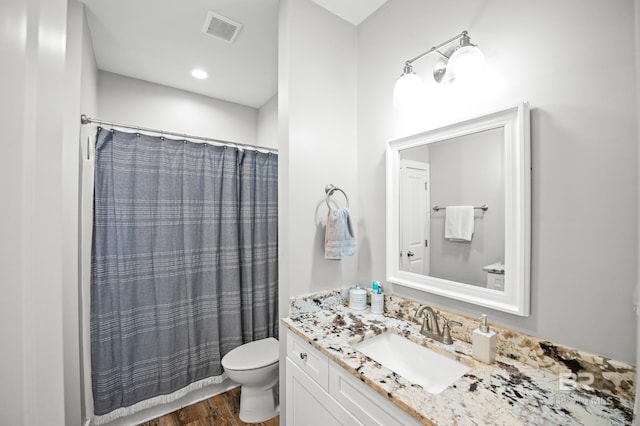 full bathroom featuring a shower with shower curtain, toilet, vanity, wood finished floors, and visible vents