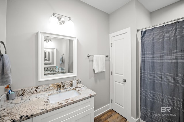 full bath with baseboards, wood finished floors, and vanity