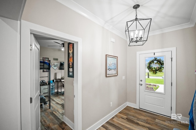 foyer entrance with ornamental molding, dark wood-type flooring, baseboards, and a chandelier