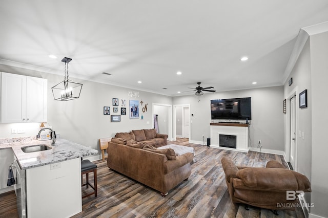 living room featuring ceiling fan with notable chandelier, dark wood-style floors, and crown molding