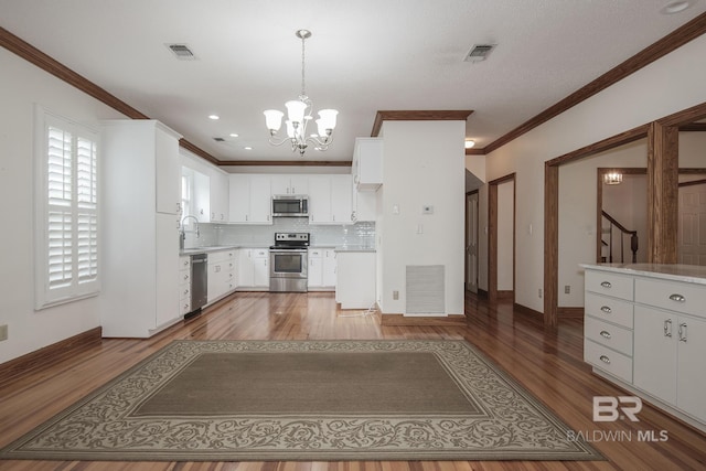 kitchen featuring sink, tasteful backsplash, pendant lighting, stainless steel appliances, and white cabinets