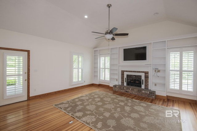 unfurnished living room with a fireplace, lofted ceiling, hardwood / wood-style flooring, ceiling fan, and built in shelves