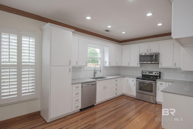 kitchen with stainless steel appliances, white cabinetry, sink, and light hardwood / wood-style floors