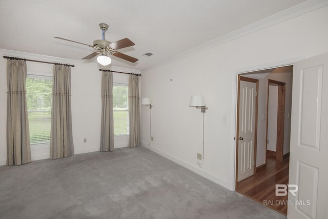 carpeted spare room with a textured ceiling, a wealth of natural light, ornamental molding, and ceiling fan