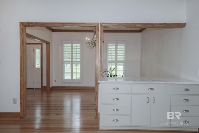 unfurnished dining area featuring crown molding, hardwood / wood-style flooring, and an inviting chandelier