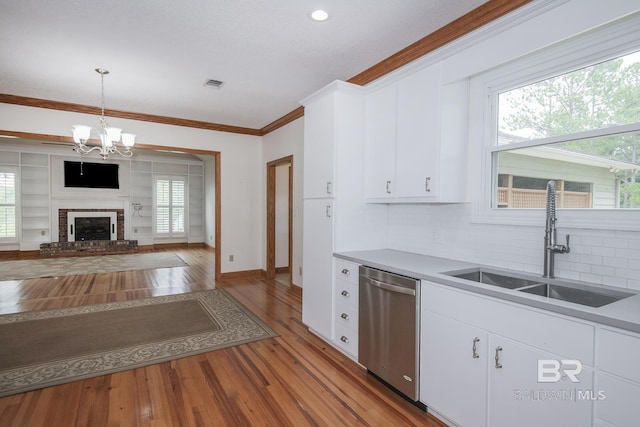 kitchen featuring dishwasher, sink, white cabinets, and decorative light fixtures