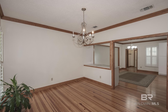 unfurnished dining area featuring hardwood / wood-style flooring, ornamental molding, and a notable chandelier